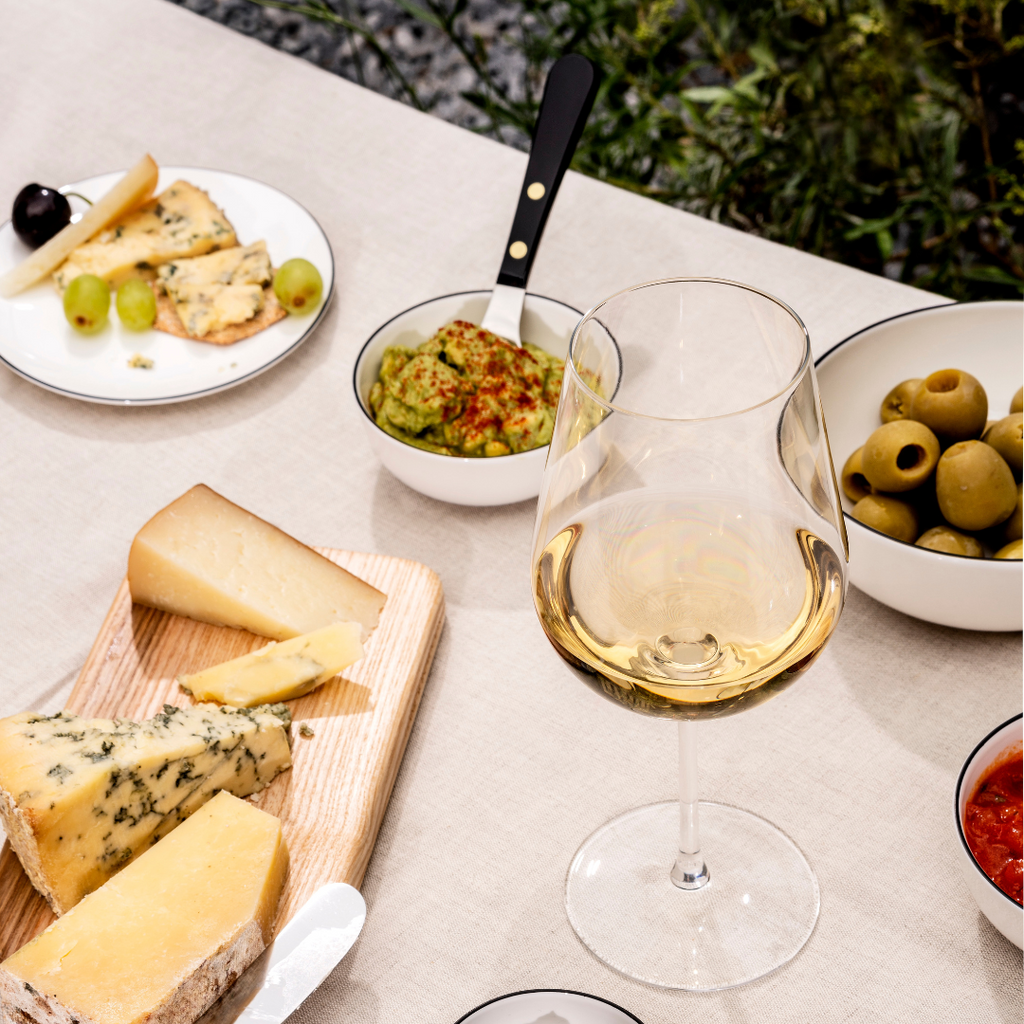 An image of a Jancis Robinson and Richard Brendon Precision Wine Glass on a table with some appetizers.